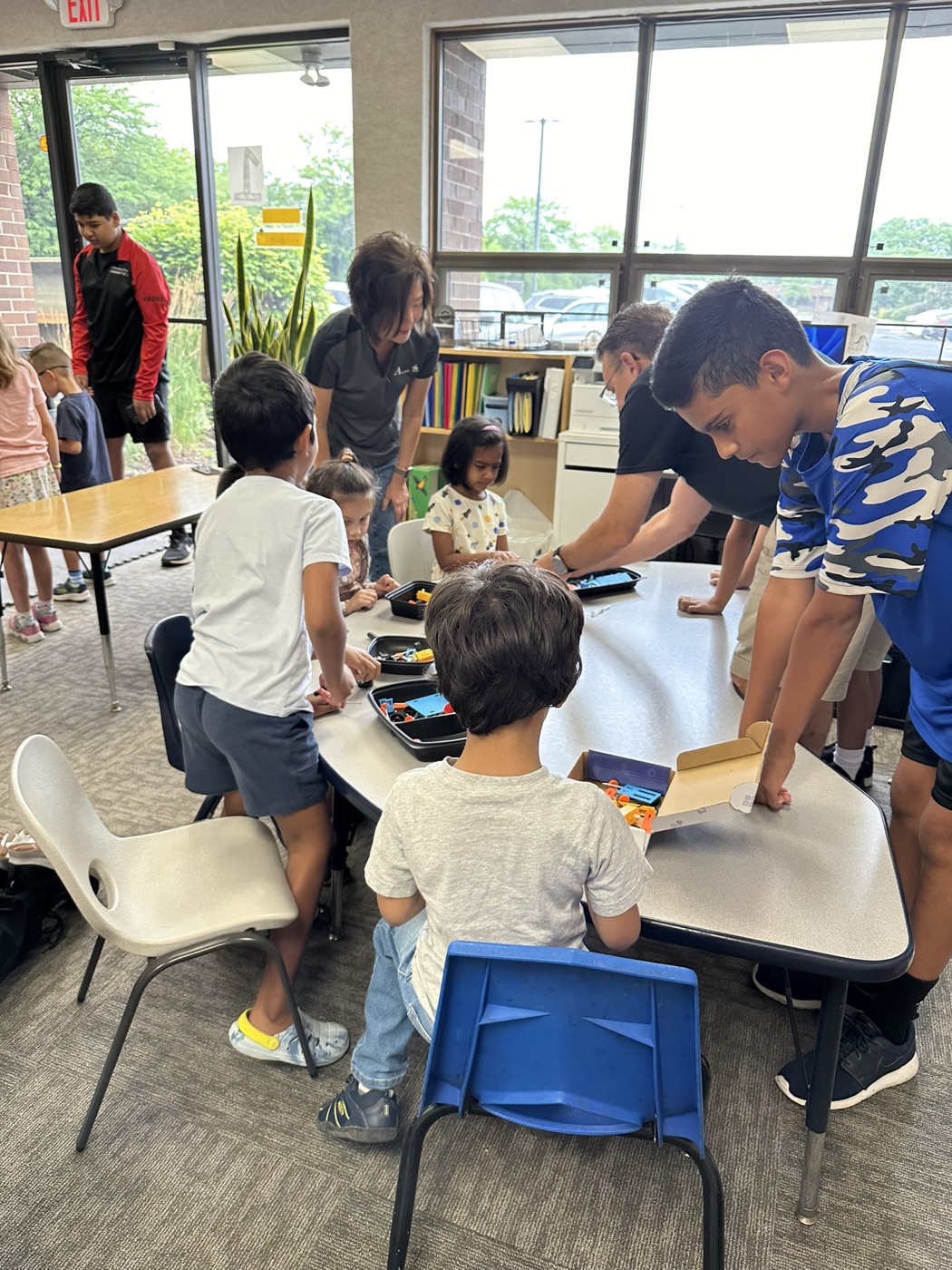 Students and mentors building with robotics kits at a classroom table